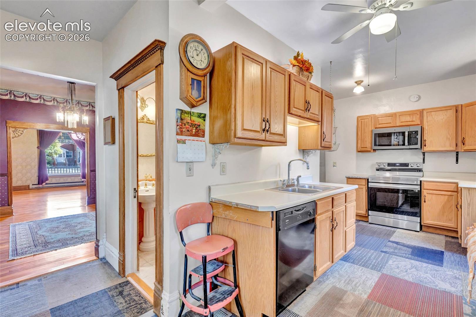 Kitchen featuring wood cabinetry, stainless steel appliances, and integrated lighting, accompanied by a bathroom with a pedestal sink
