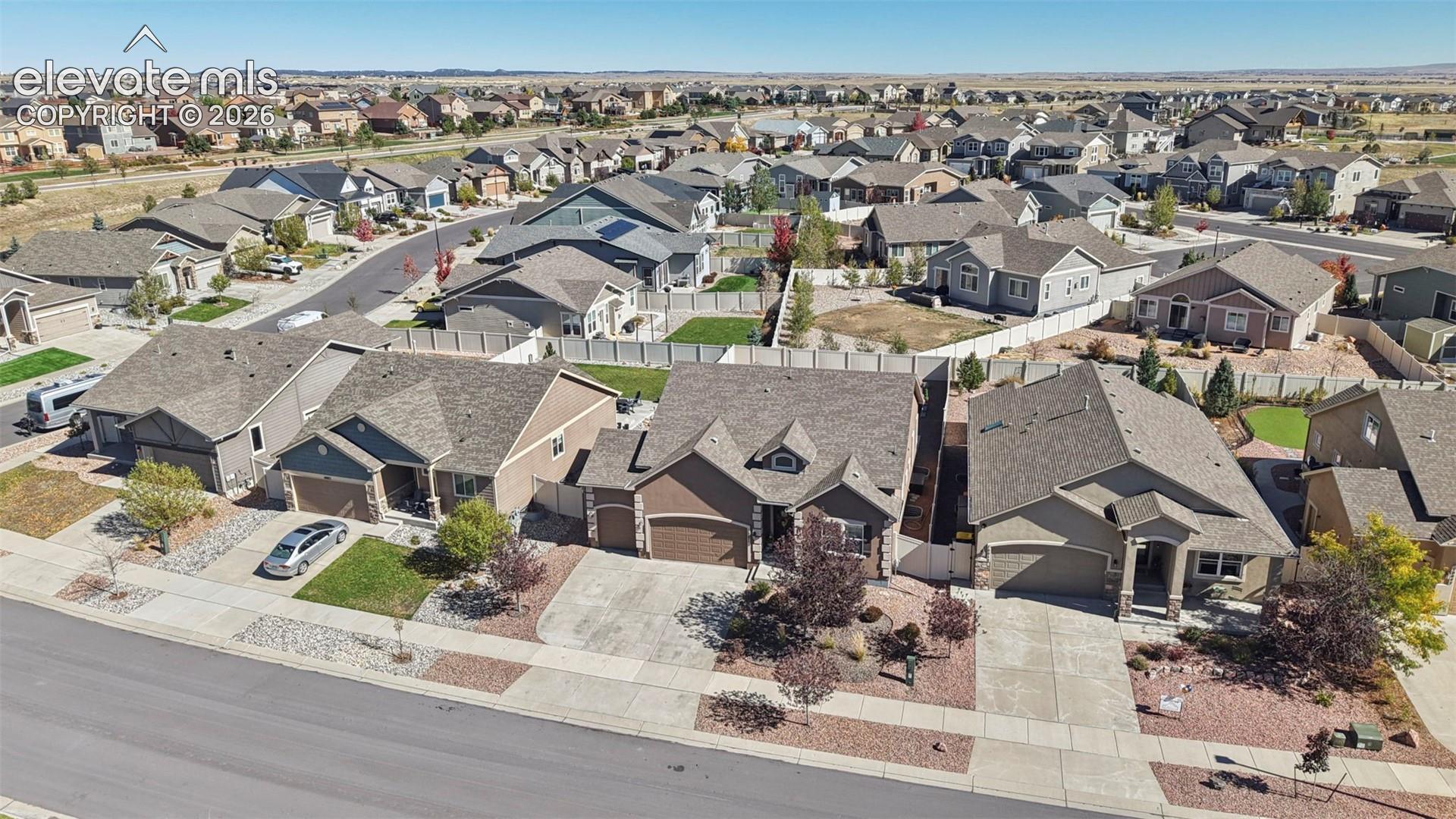 Aerial perspective of a suburban neighborhood featuring paved streets, asphalt-shingled roofs, attached multi-car garages, and concrete driveways