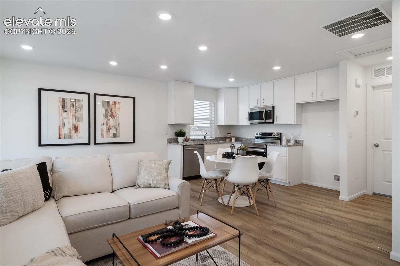 Open-concept living area with wood-finish flooring, recessed lighting, and white walls
*photos of a model home*