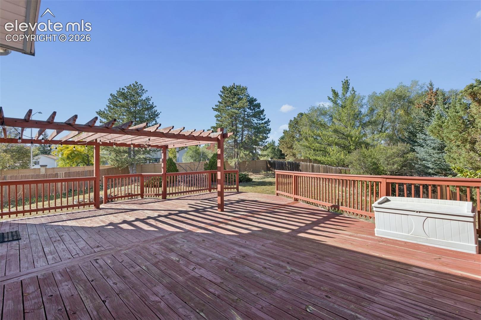 Expansive wood-finish deck with a built-in pergola and perimeter railing