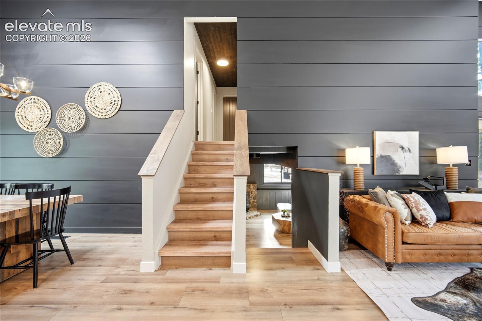 Interior featuring expansive horizontal shiplap walls, wood-finish flooring, and an open staircase with a wooden handrail