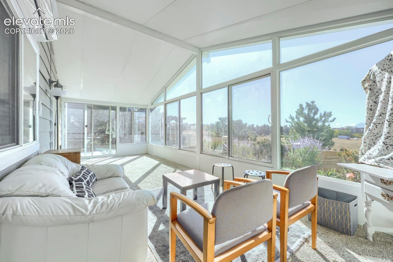 Sunroom featuring expansive floor-to-ceiling windows, vaulted ceiling, and exterior sliding glass doors
