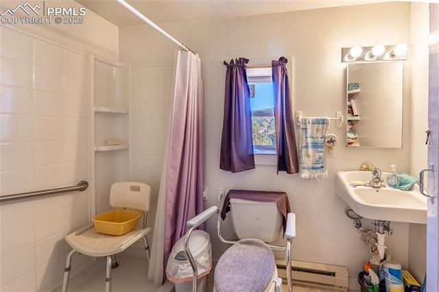 Bathroom with a baseboard radiator and a shower with shower curtain