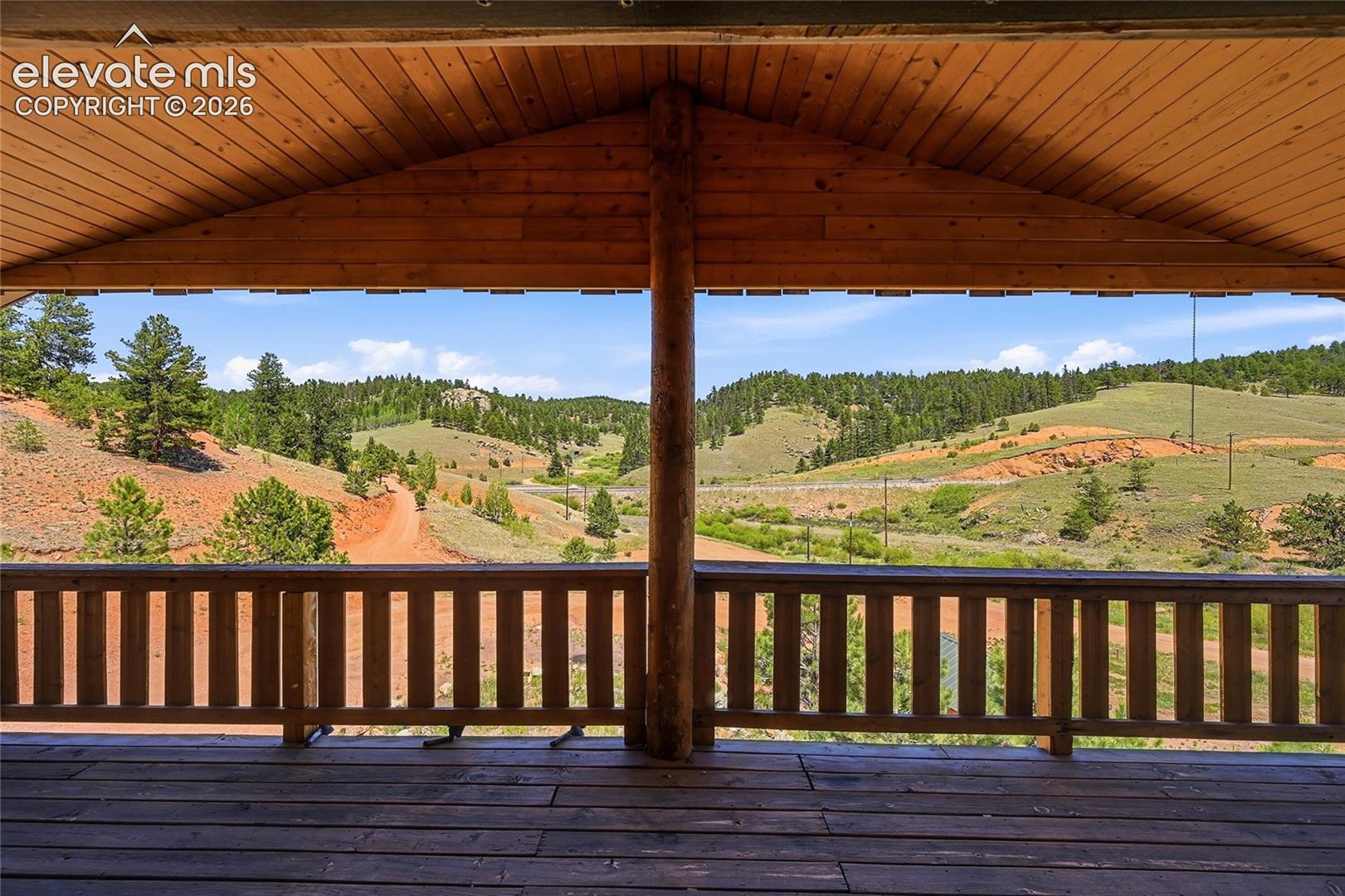 Covered outdoor deck with wood flooring and wood railing