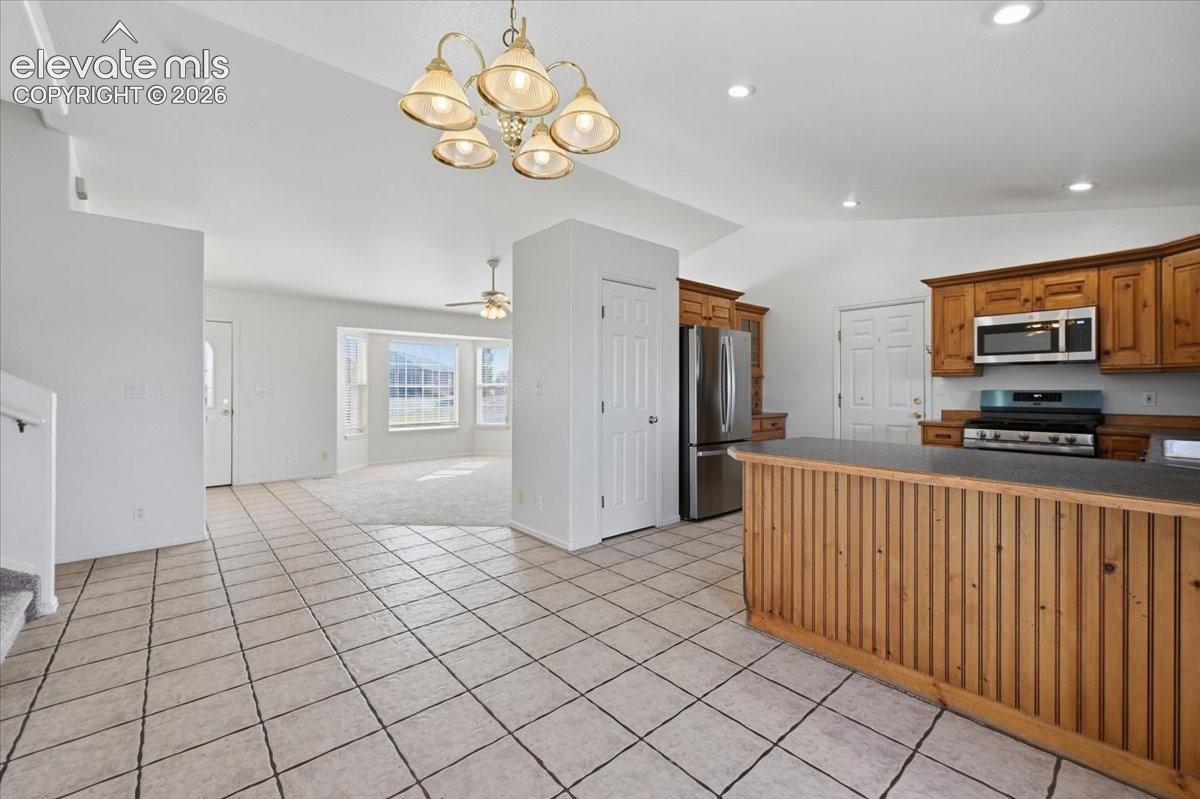 Kitchen featuring wood cabinetry, stainless steel appliances, and a breakfast bar with a paneled wood front
