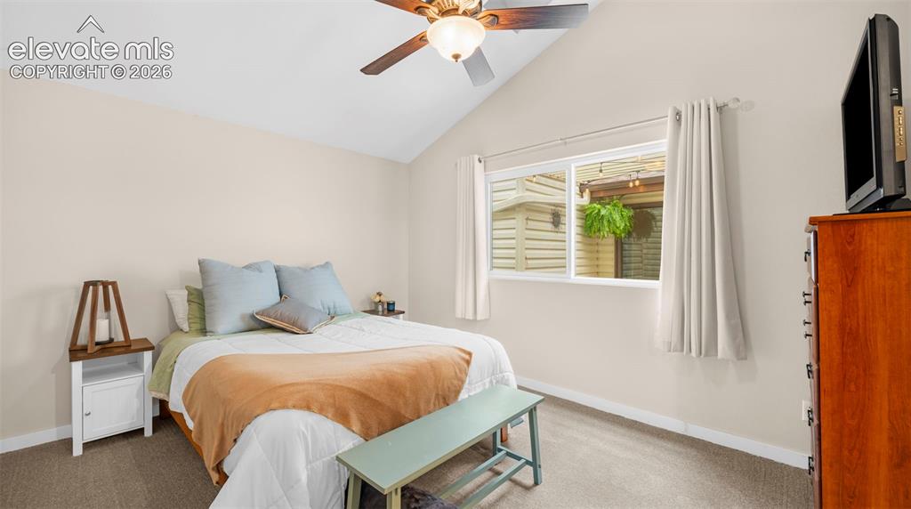 Vaulted ceiling with an overhead fan, single pane window, light-toned walls, neutral carpet flooring, and white trim