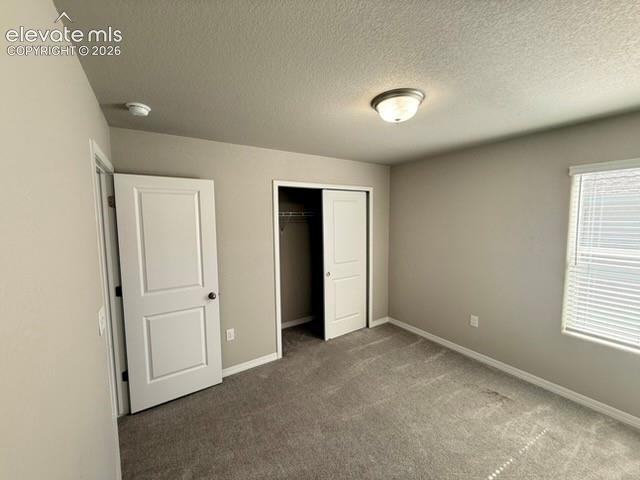 Neutral tone wall paint, textured ceiling, flush mount ceiling light fixture, window with blinds, and gray carpet flooring