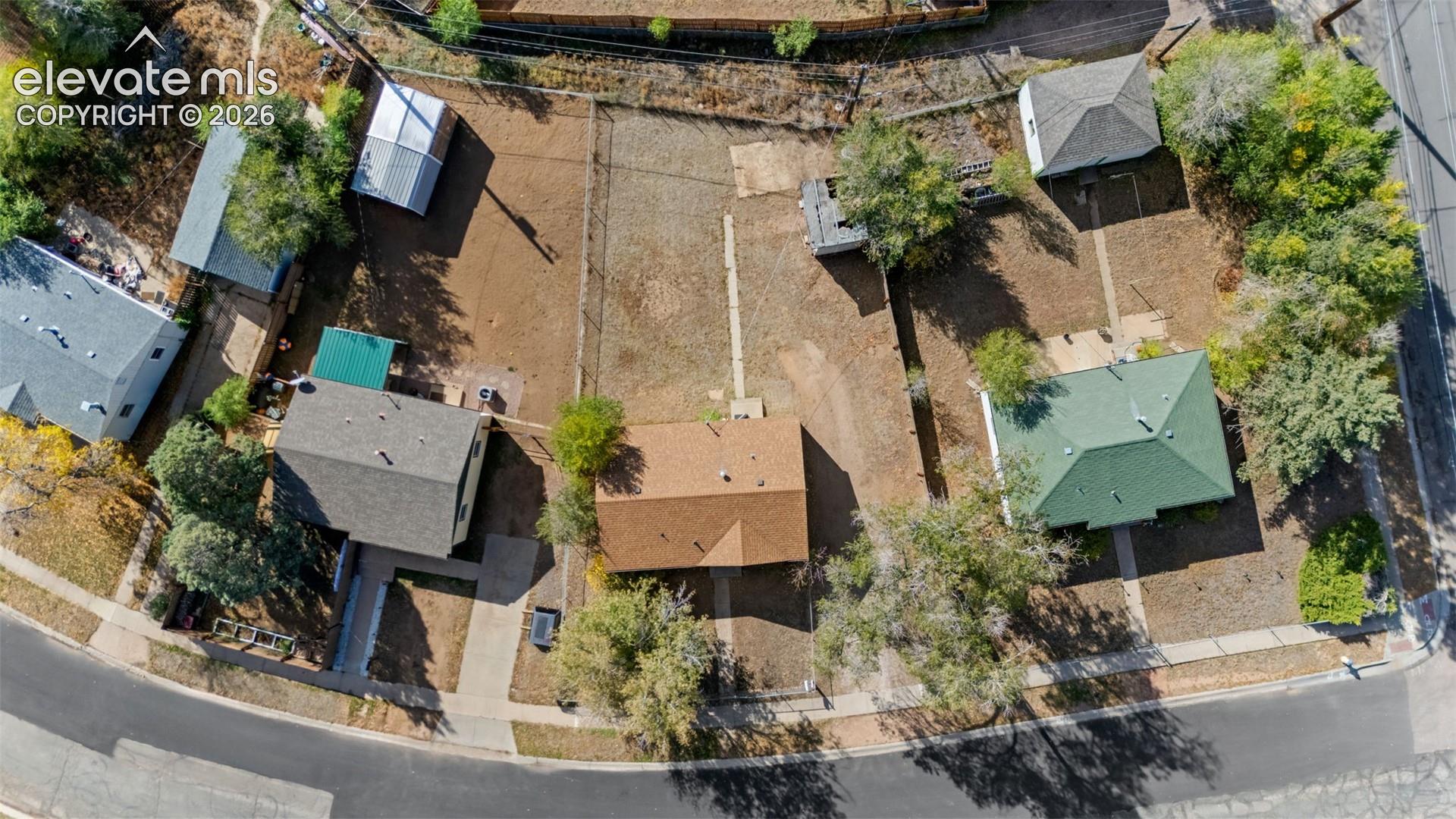 Aerial perspective of properties featuring asphalt-shingle roofs, concrete walkways, and established mature trees