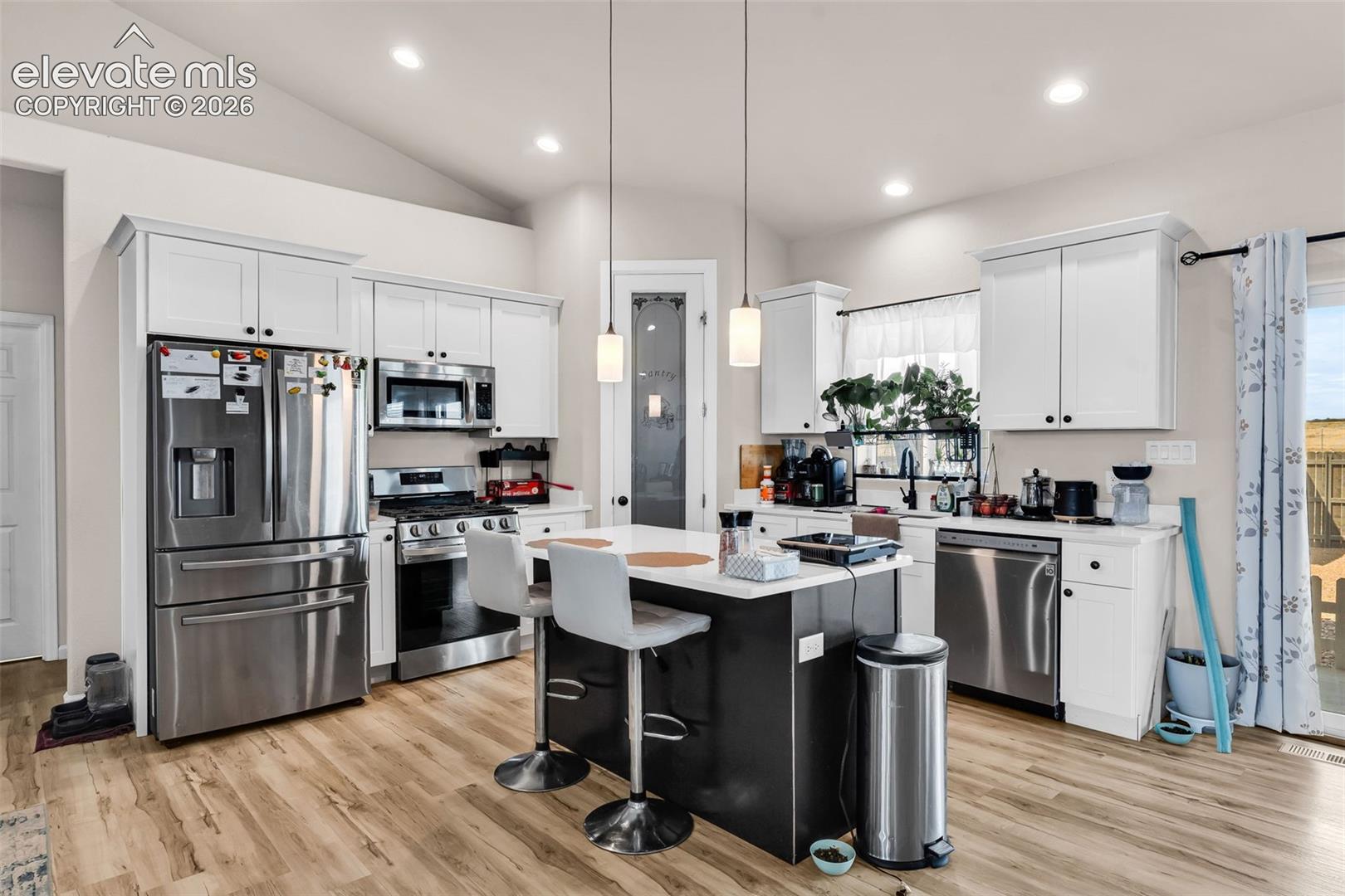 Kitchen featuring wood-finish flooring, white cabinetry, and stainless steel appliances