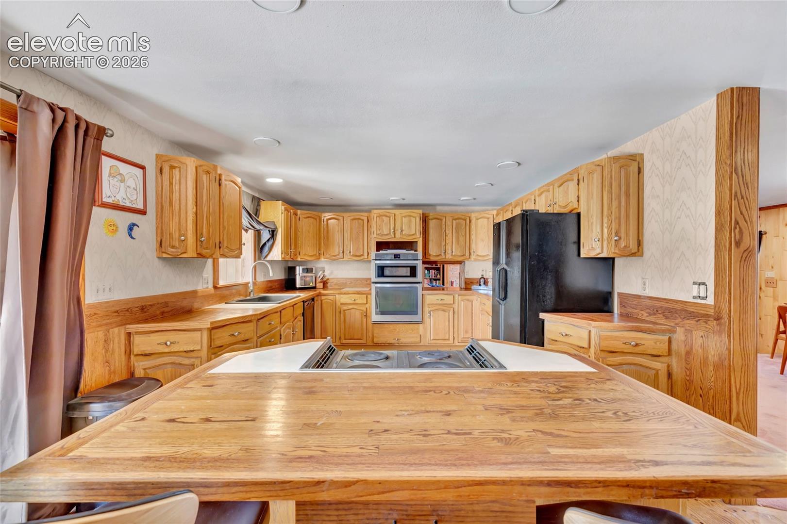 Kitchen featuring wood cabinetry, integrated wall oven, and a center island with built-in cooktop