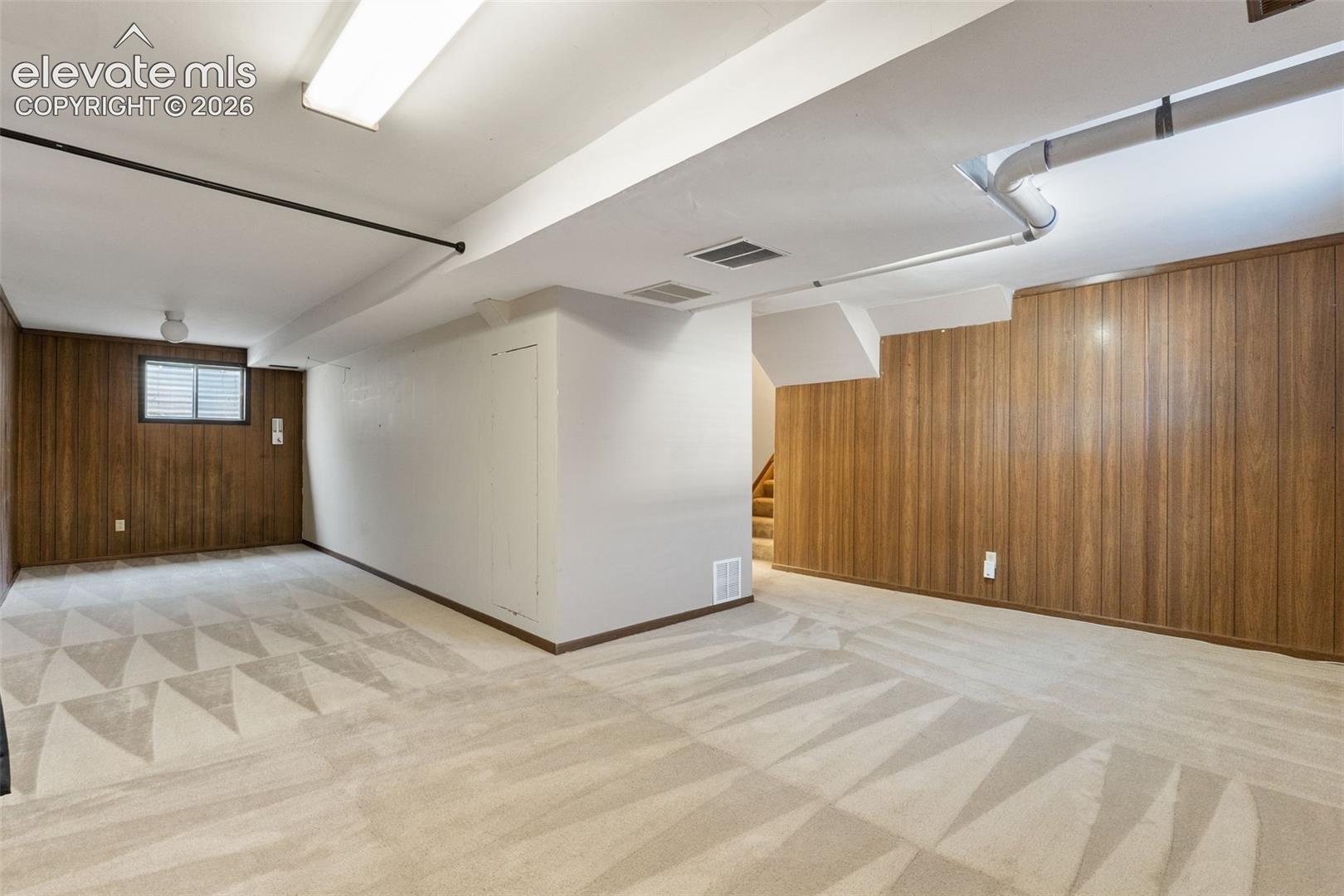 Finished room featuring wood-paneled walls, carpeted flooring, and a sliding window