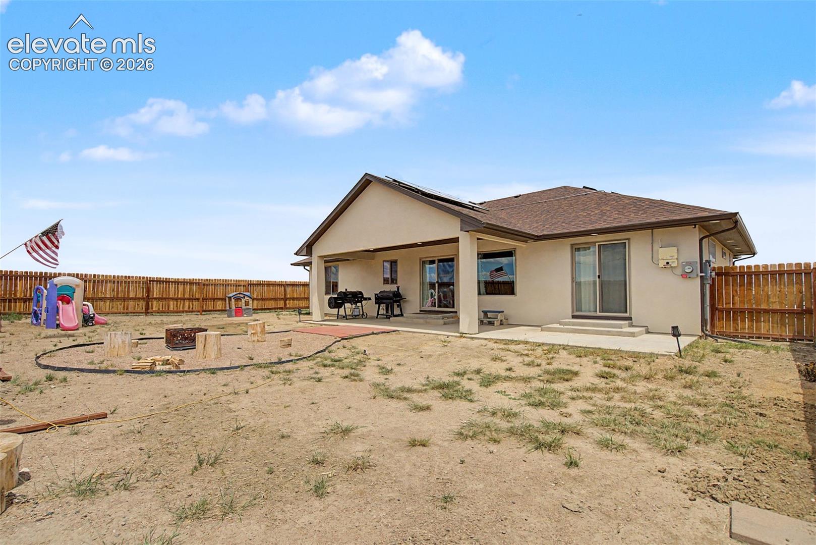 Rear exterior featuring a covered patio, a separate concrete patio, and a wood privacy fence