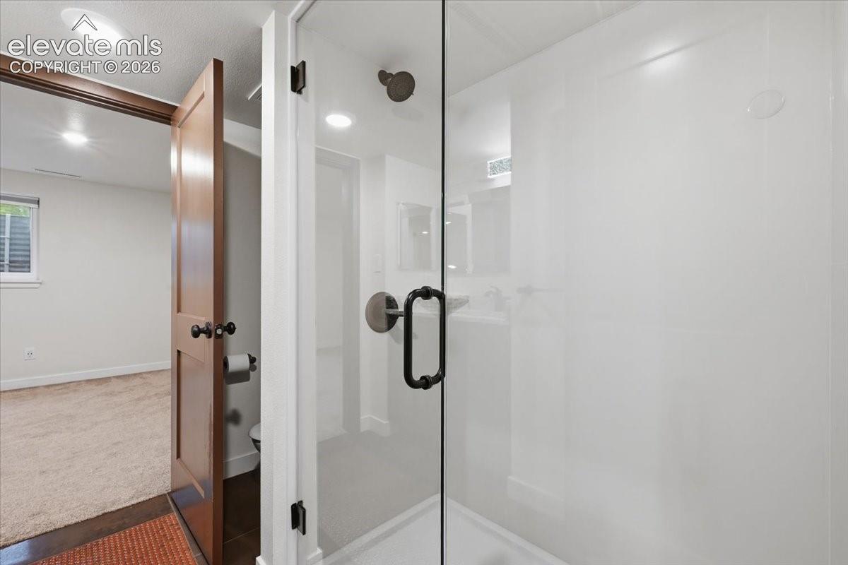 Frameless glass shower enclosure, recessed lighting, and custom flooring