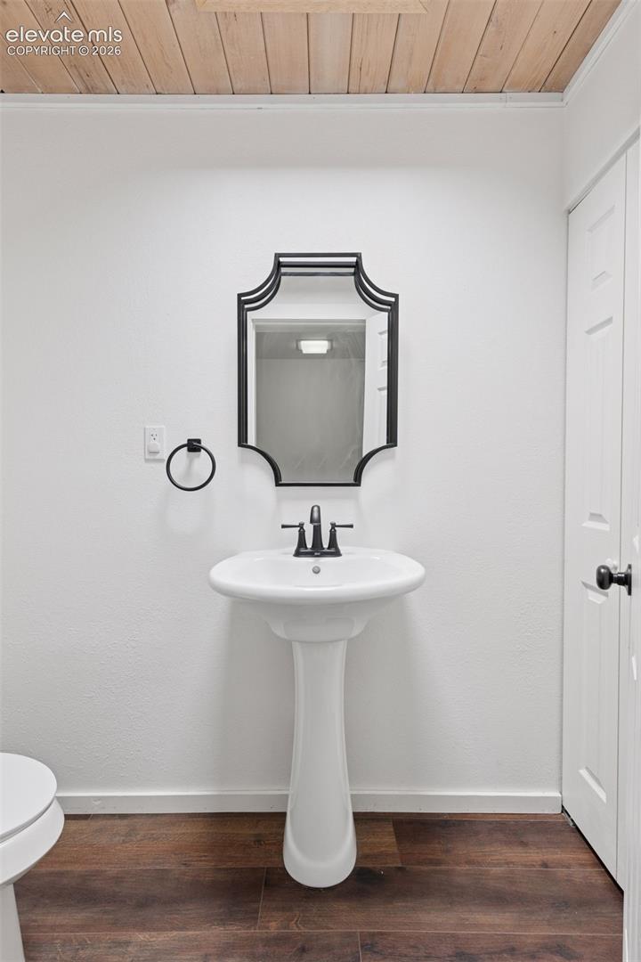 Half bath featuring pedestal sink, mirror, and overhead lighting.
