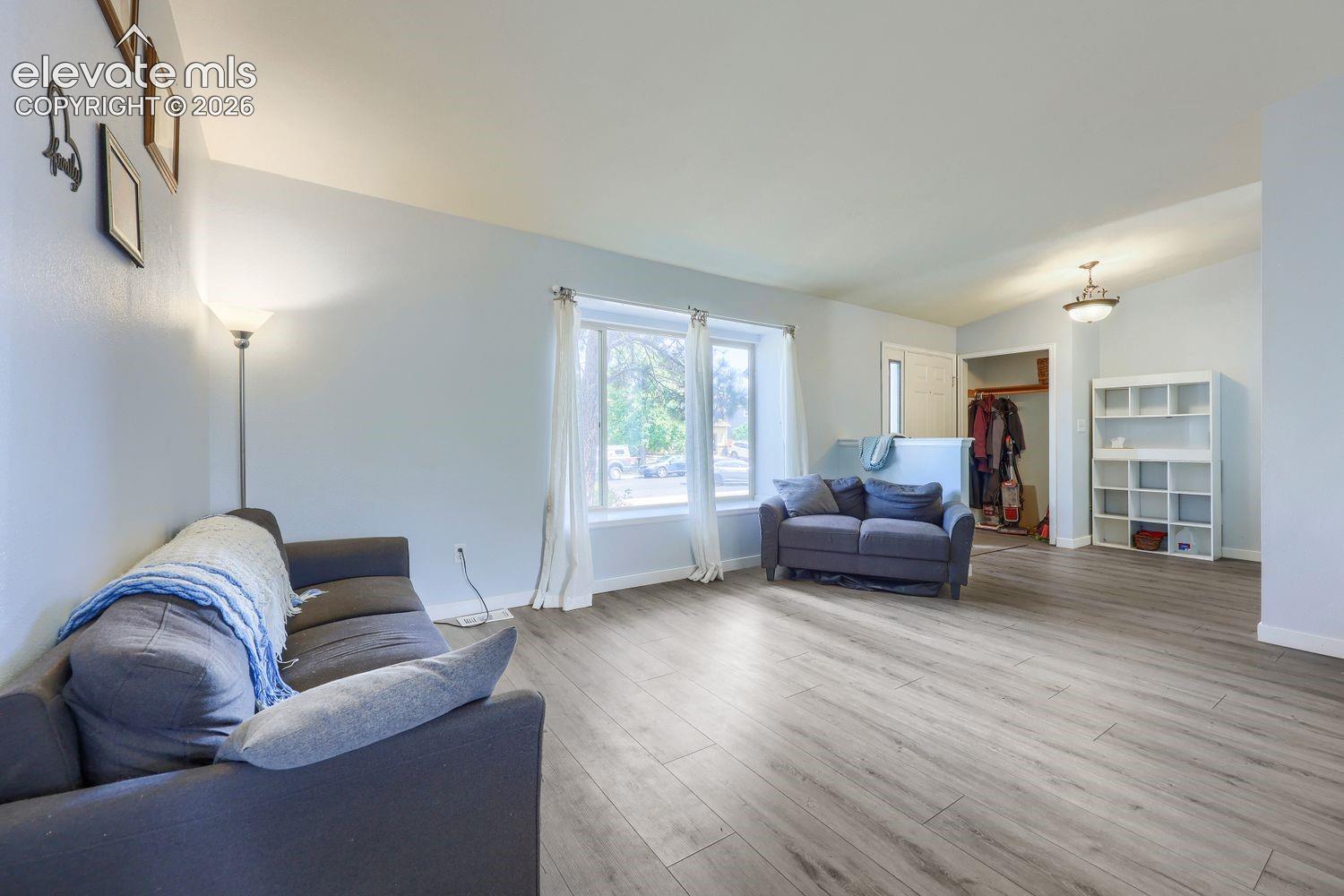 Wood-finish flooring, light-colored walls, multiple windows, and a built-in shelving unit