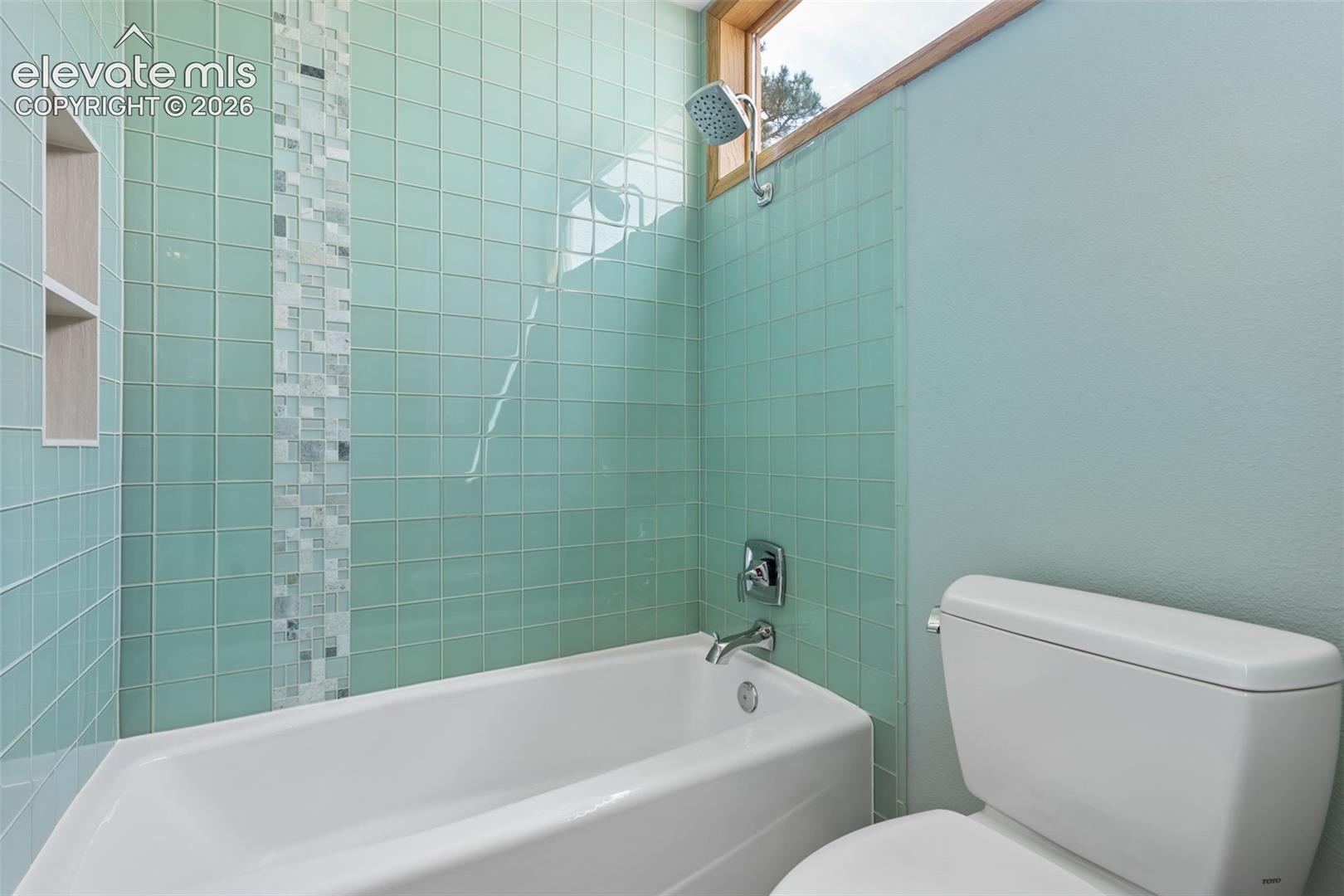 Remodeled bath featuring beautiful glass tile with granite counters, double sinks, and tile flooring.  Nice big window lets lots of natural light into this home!