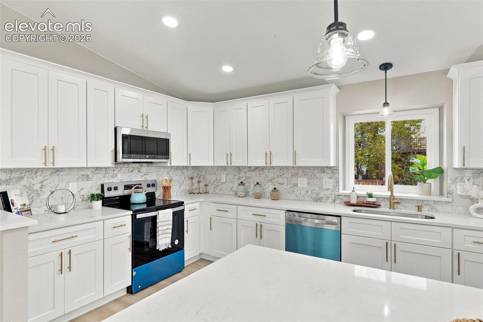 Kitchen featuring white shaker-style cabinetry, stone-finish countertops, full-height stone-look tile backsplash, stainless steel appliances, and pendant lighting