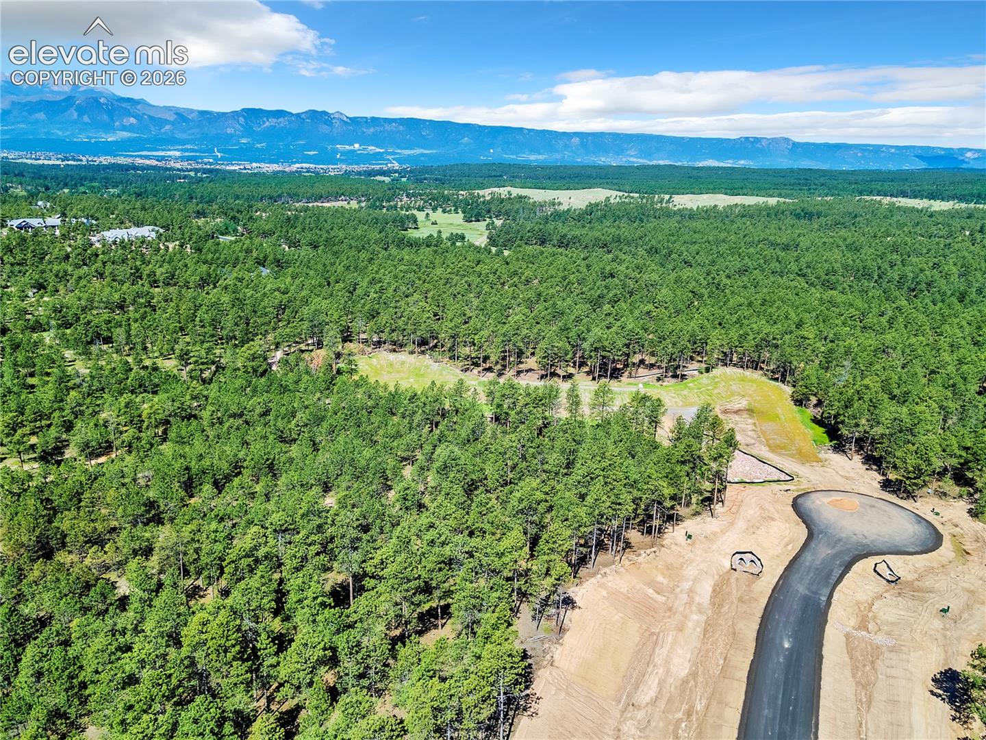 Aerial view of expansive woodland lot featuring mountainous topography and paved cul-de-sac access