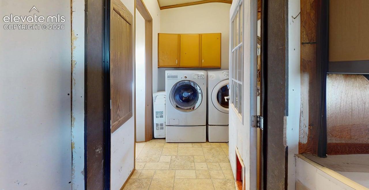 Laundry room with light stone finish floors, cabinet space, and independent washer and dryer