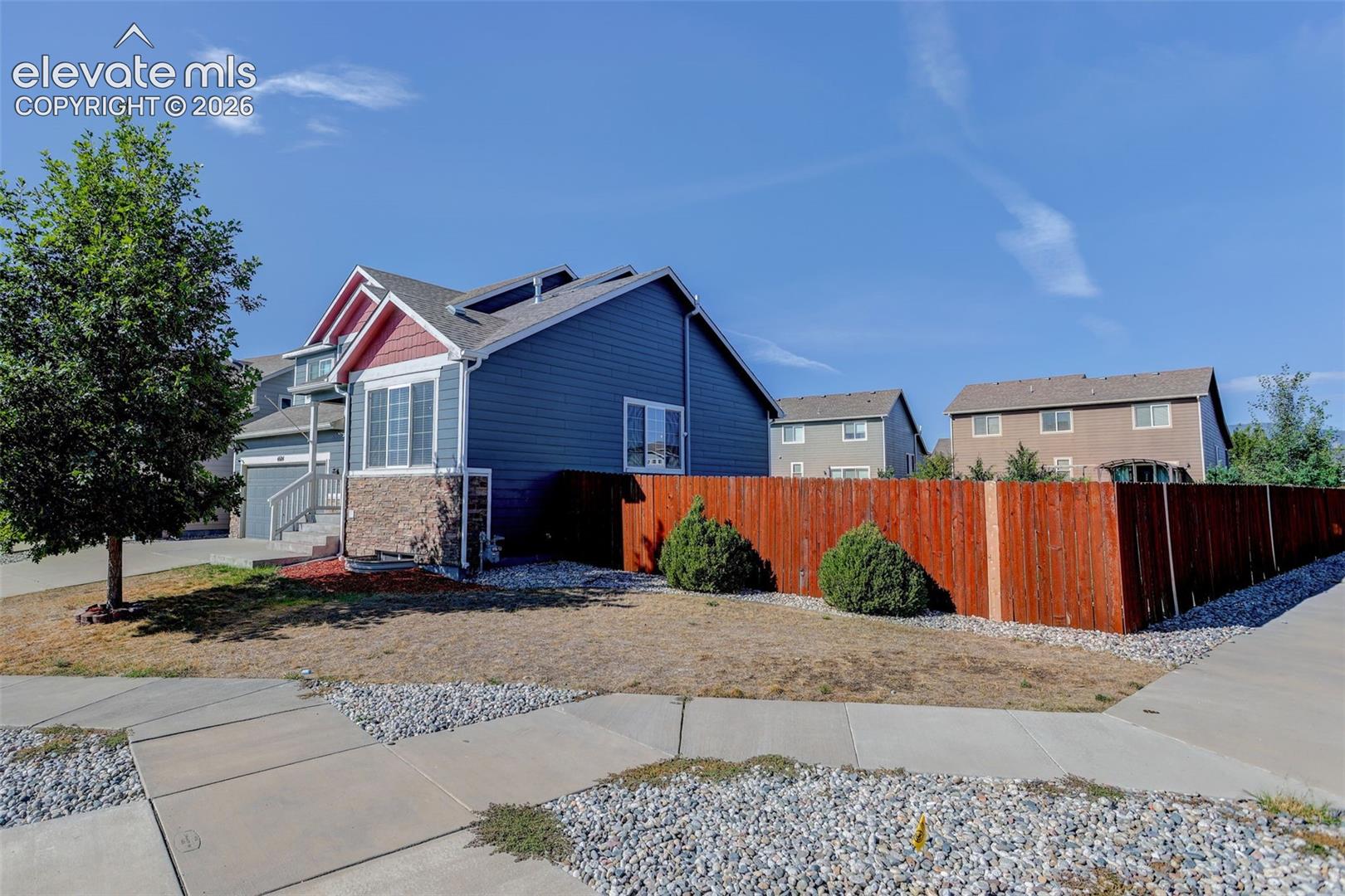 Siding exterior with stone accents, fenced perimeter, and established landscaping