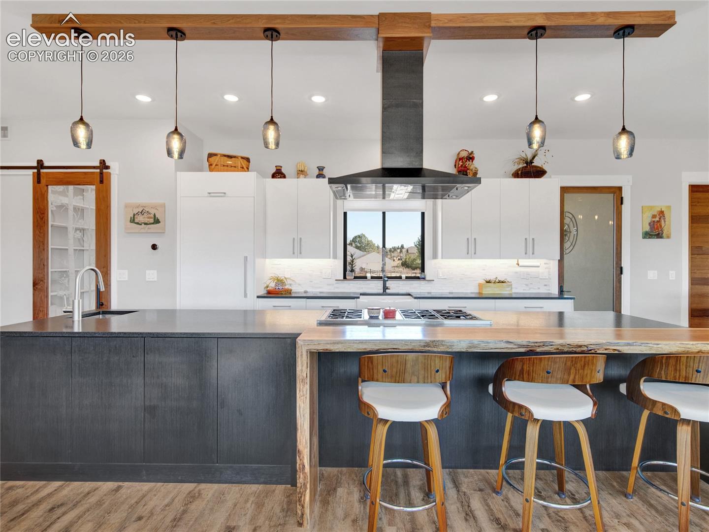 Modern kitchen featuring a large island with dark cabinetry and a wood-finish countertop