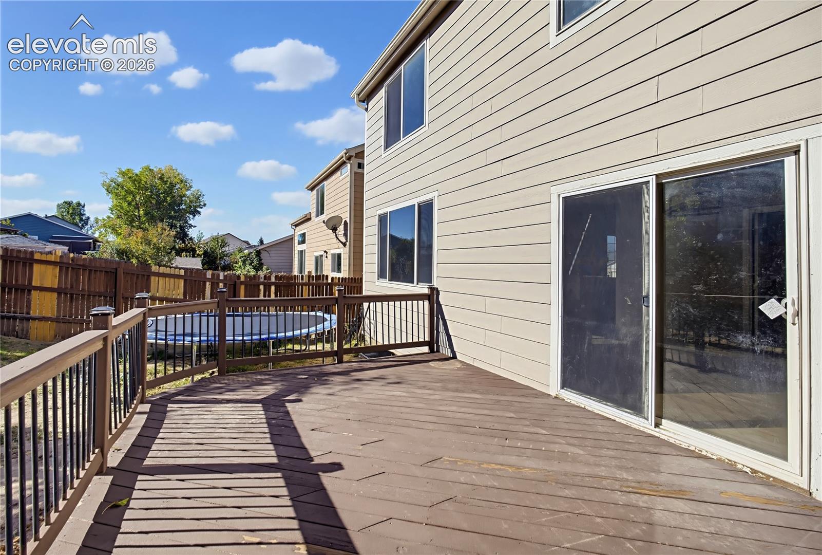 Rear exterior featuring a multi-level wood deck with metal balusters, horizontal siding, and a sliding glass door