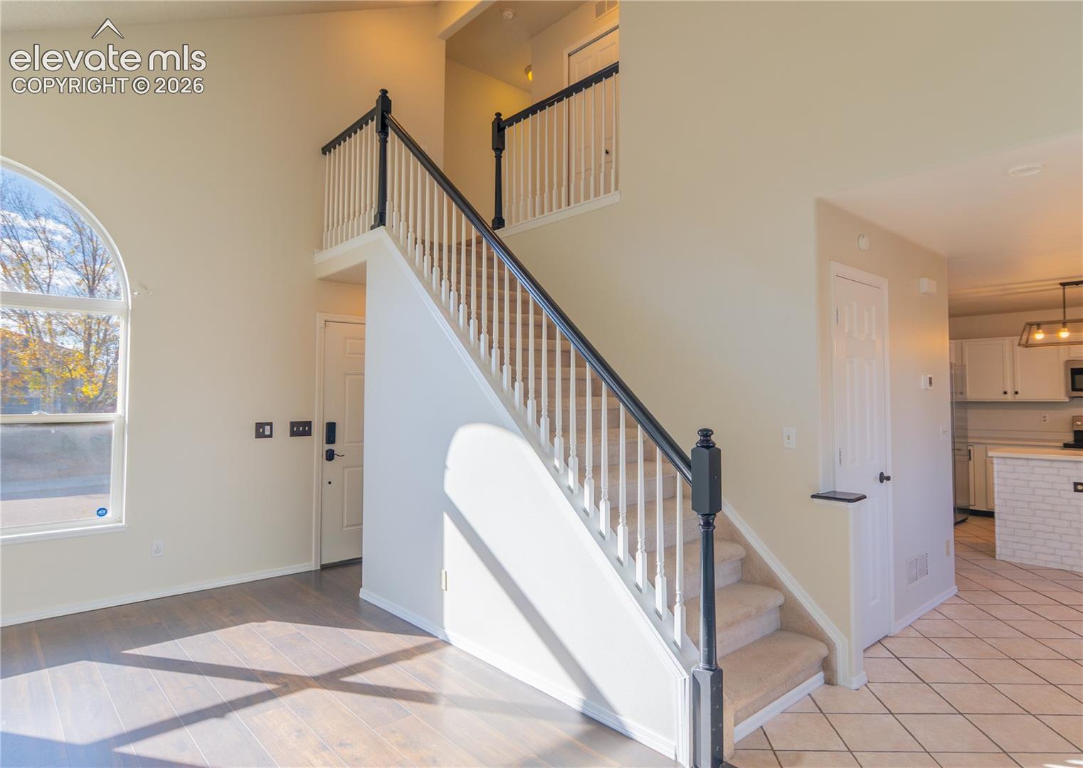 An open staircase and upper-level overlook add architectural interest to the main living area.