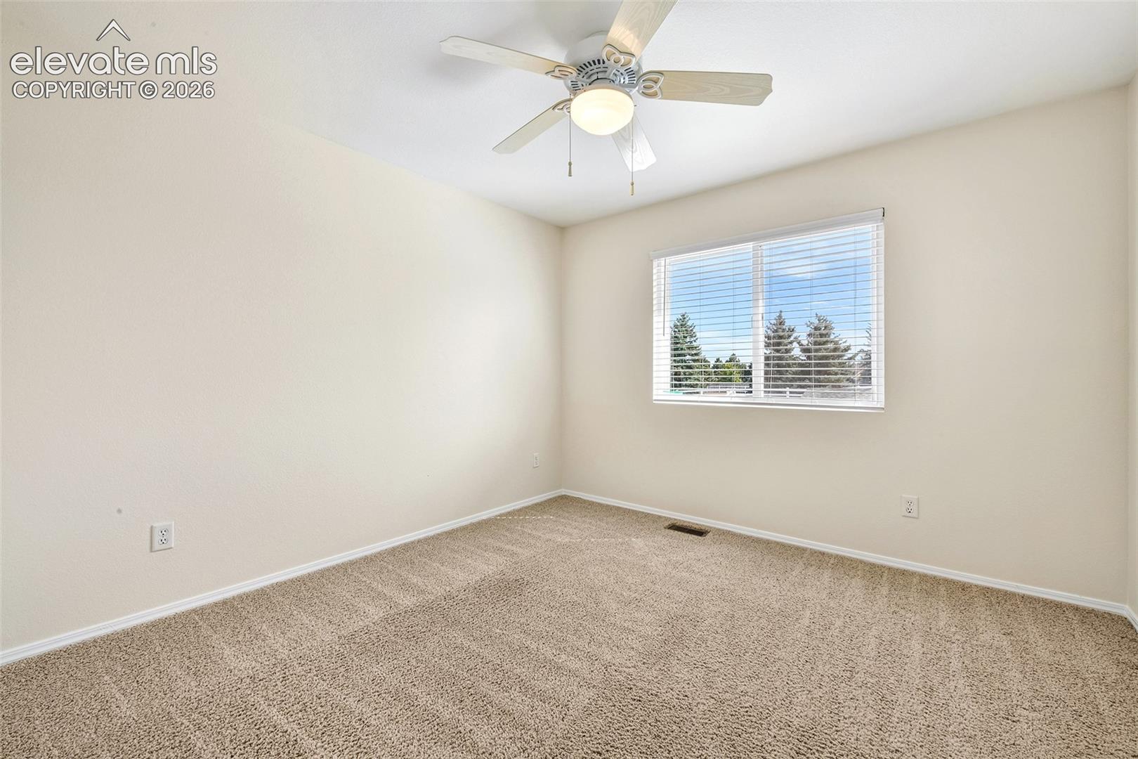 Light-colored walls, broadloom carpeting, ceiling fan with integrated lighting, and a window with horizontal blinds