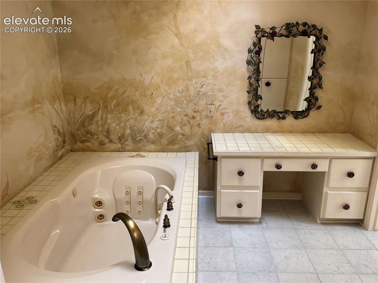 Built-in jetted tub with brass fixtures and tiled surround