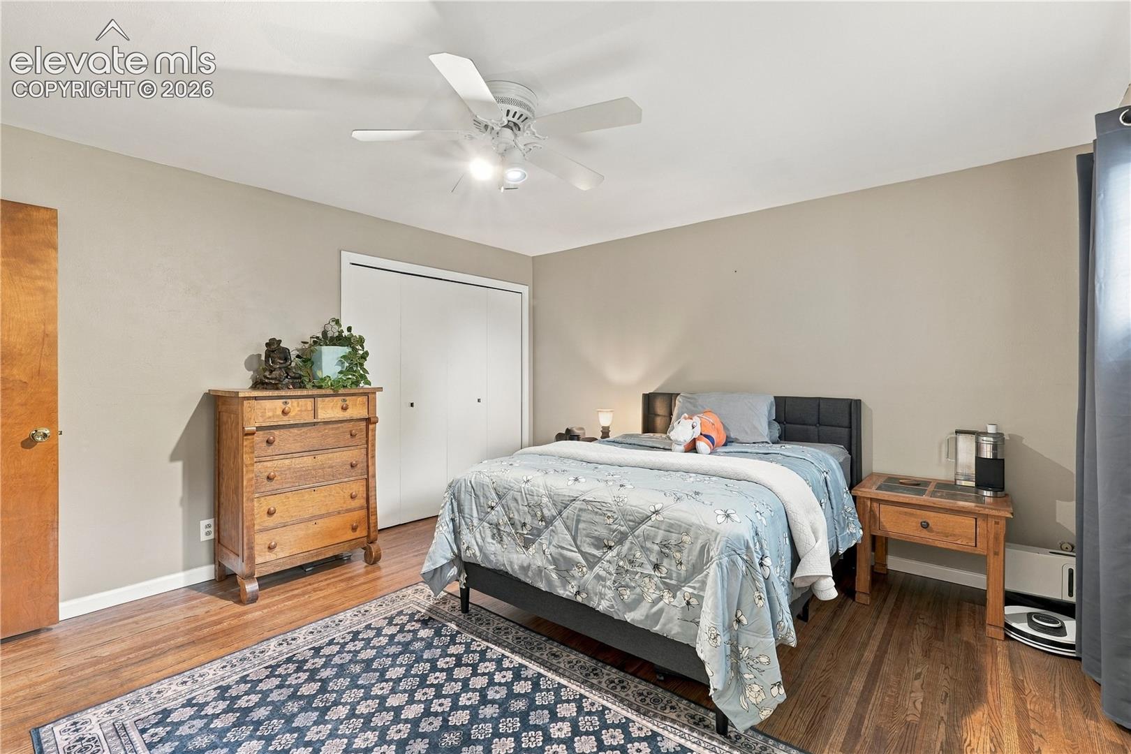 Wood-finish flooring, ceiling fan with integrated lighting, and white bi-fold closet doors