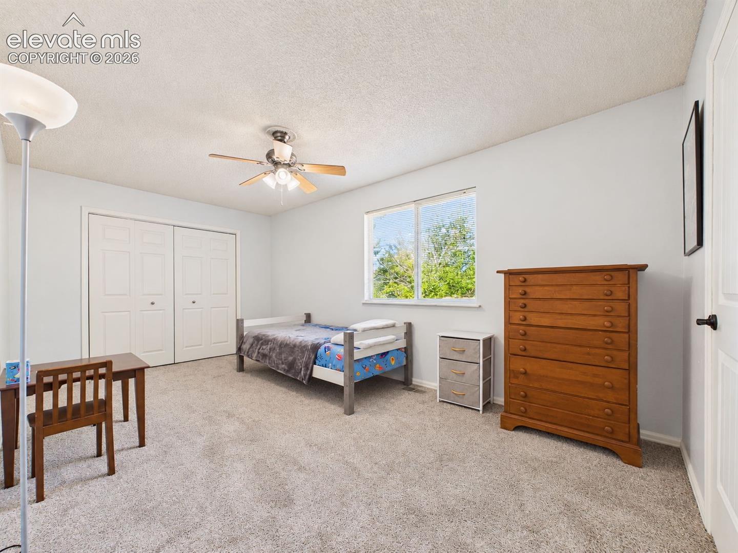 Generously sized bedroom offers carpeting, a ceiling fan, a large window, and wide double-door closet space for convenient storage.