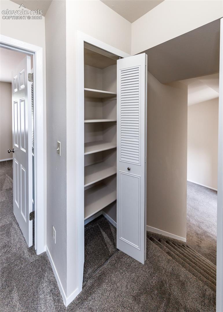Built-in shelving with a louvered bifold door, painted white trim, and light gray wall color