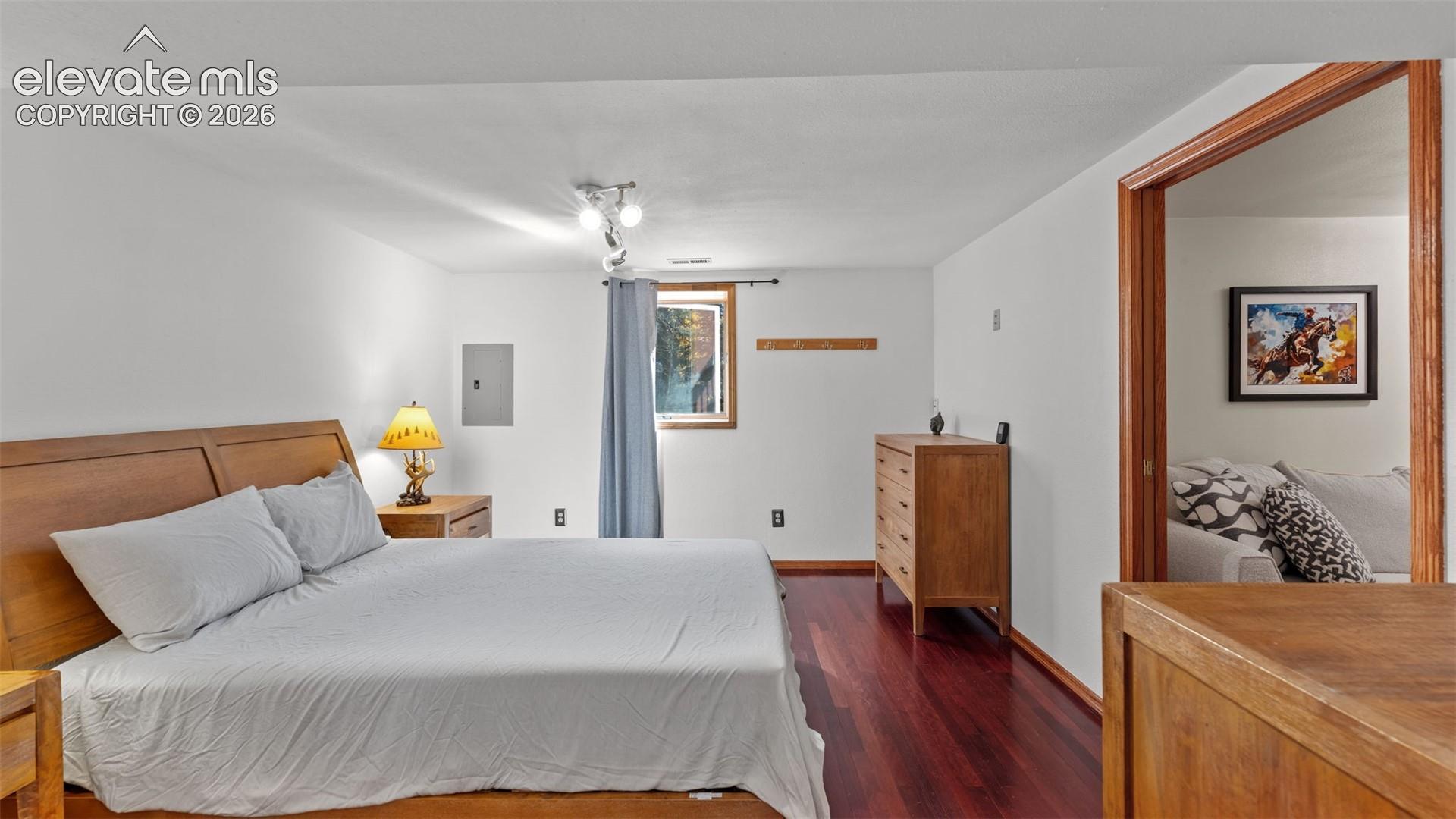 Wood-finish flooring, recessed track lighting, and window with wood trim