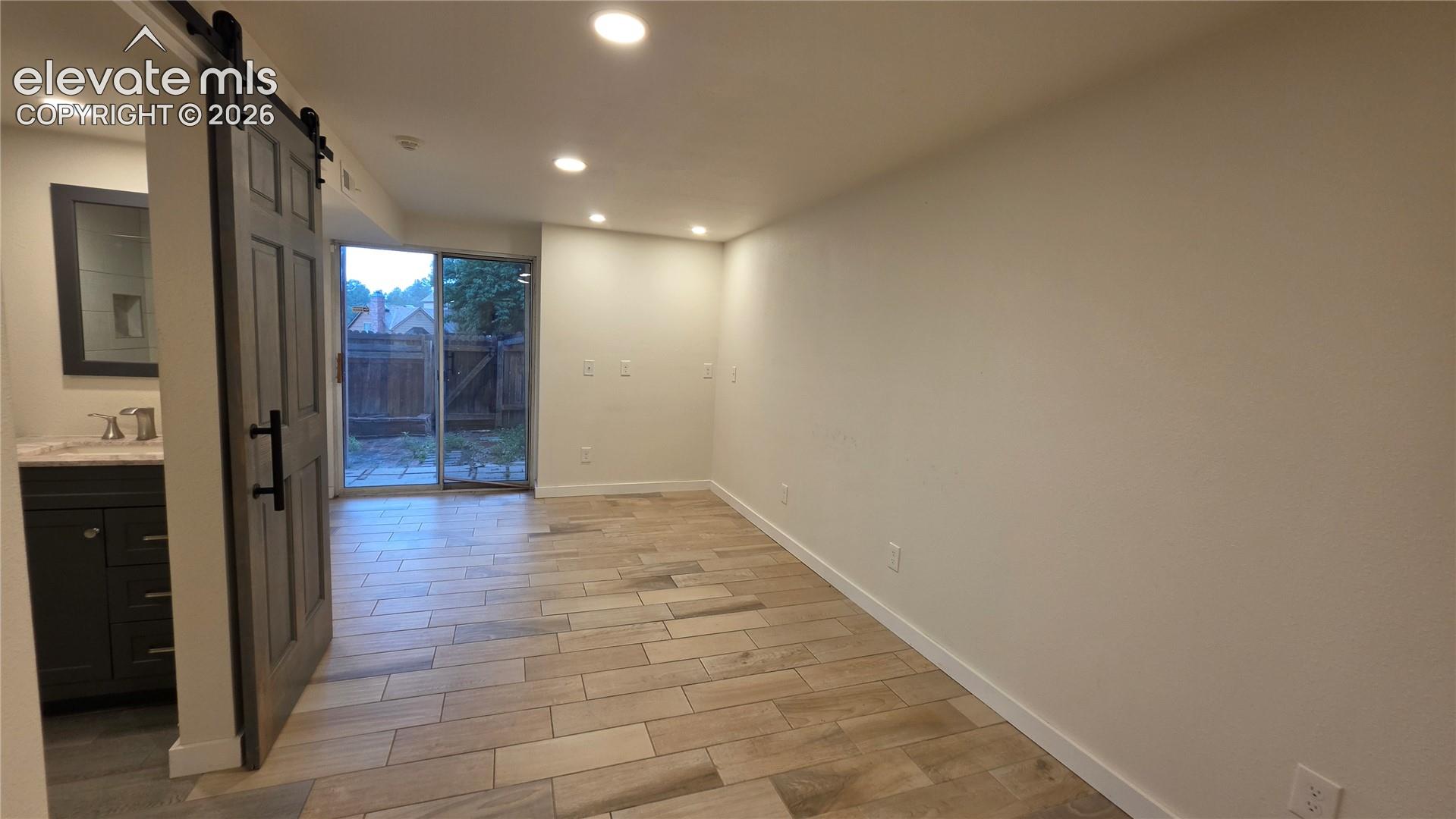 Recessed lighting, wood-finish flooring, sliding glass door, barn door entry, vanity with countertop and sink