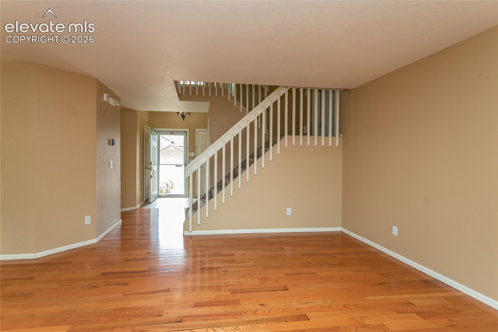 Living room with stairs to the other levels of the home and the entryway, front door