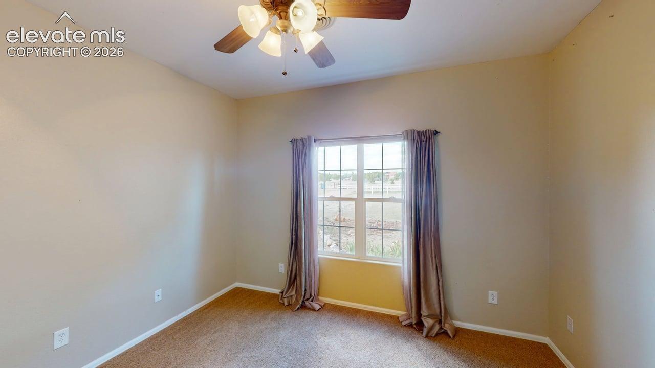 Wall-to-wall carpeting, window with grid panes, and a ceiling fan with integrated lighting