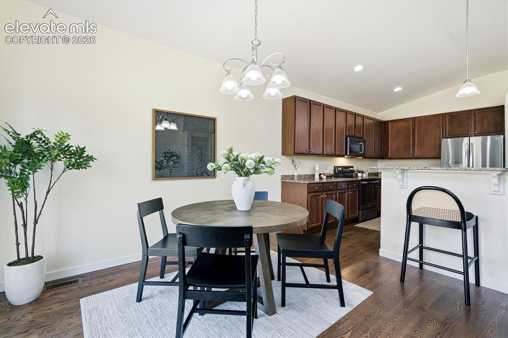Hardwood-finish flooring, recessed lighting, chandelier lighting, and a breakfast bar with stone-finish countertop