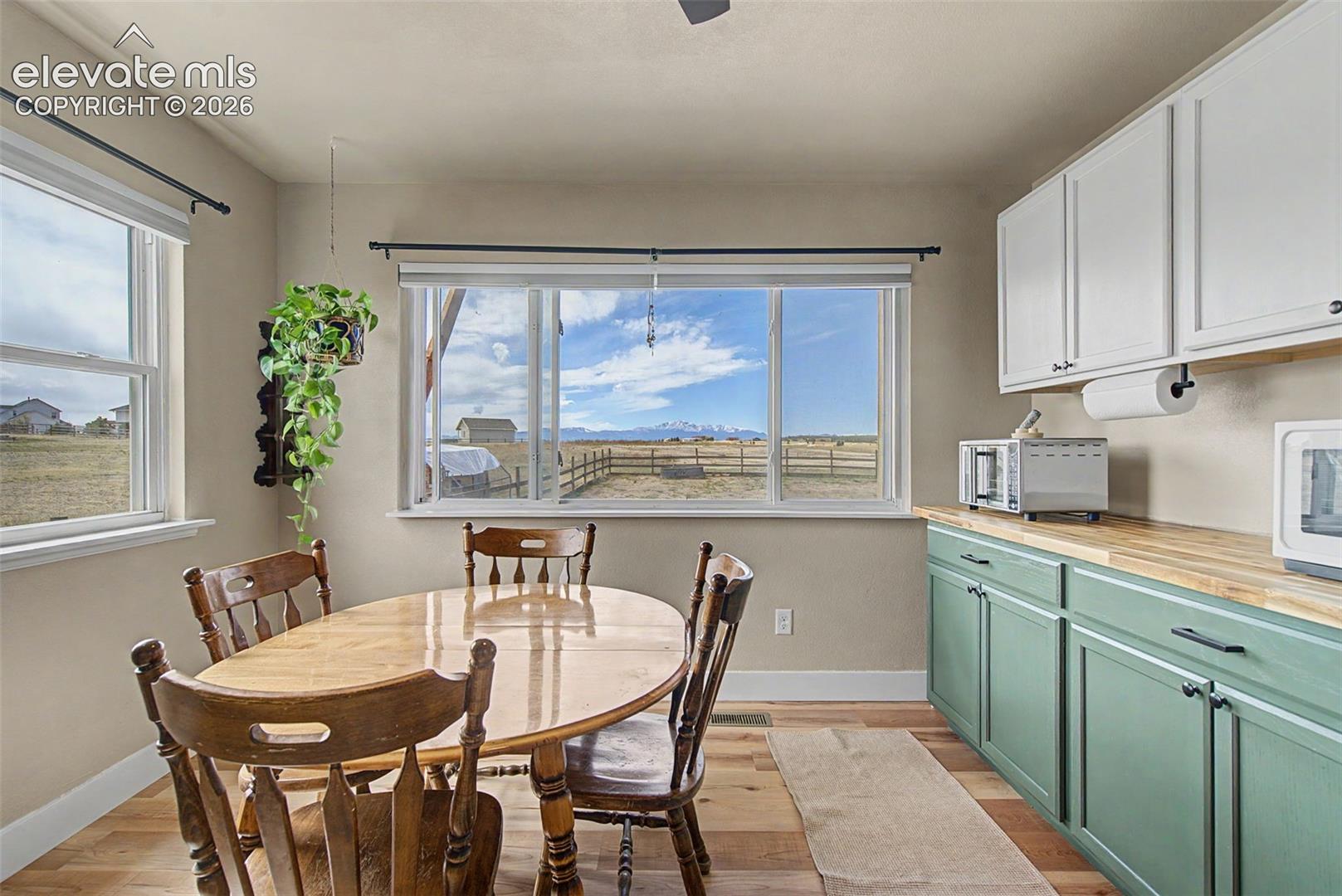 Large windows with mountain scenery, wood-finish flooring, butcher block countertops, and dual-tone cabinetry
