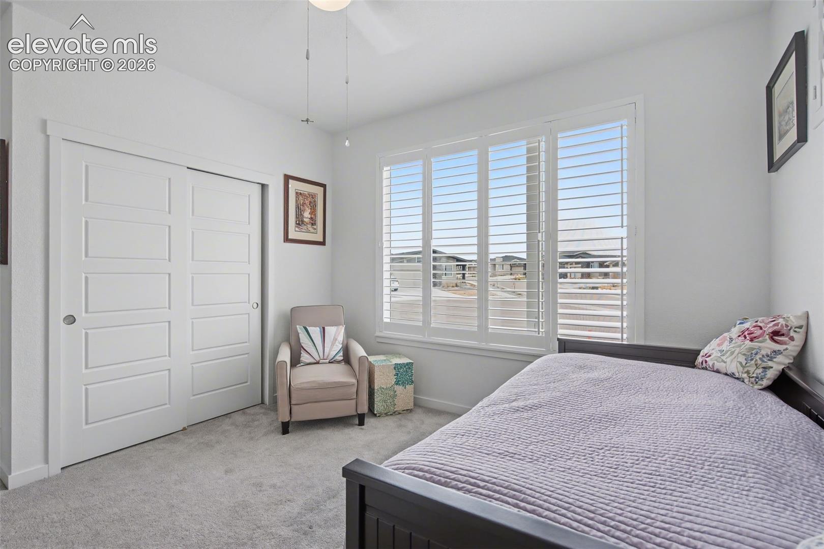 Bedroom featuring light colored carpet, a closet, and a ceiling fan