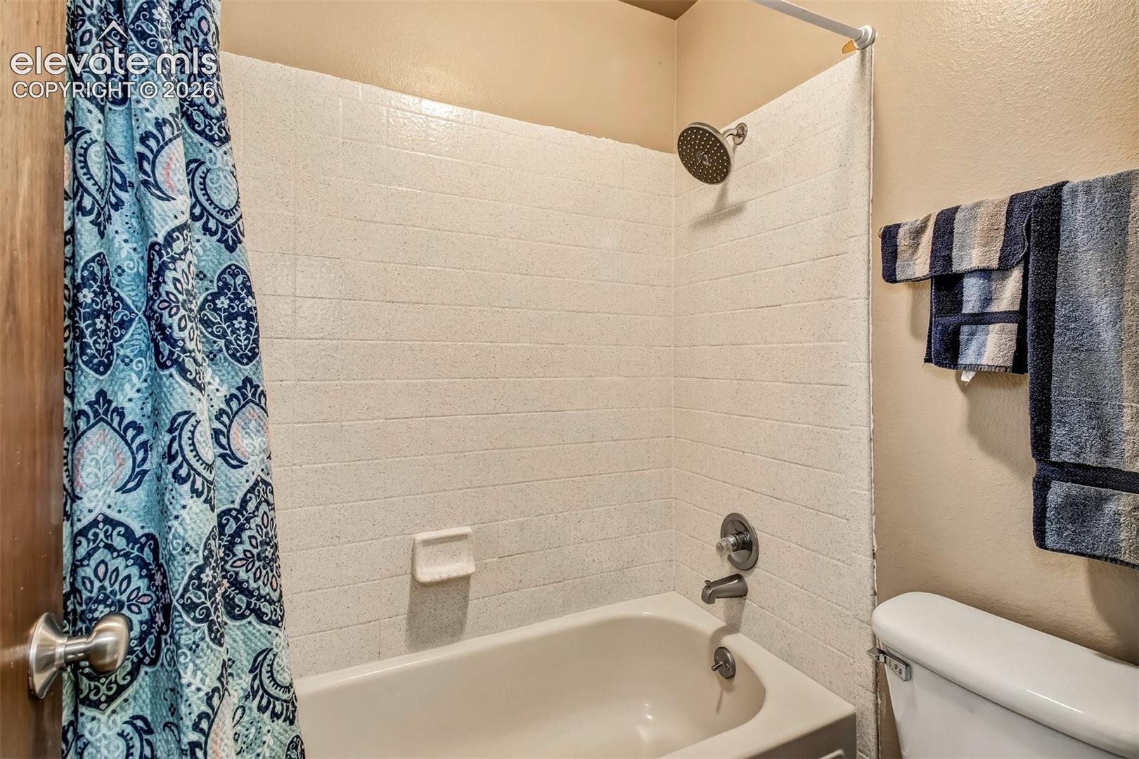 Full-height shower surround with subway-style tiling, built-in soap dish, round rainfall shower head, and chrome plumbing fixtures