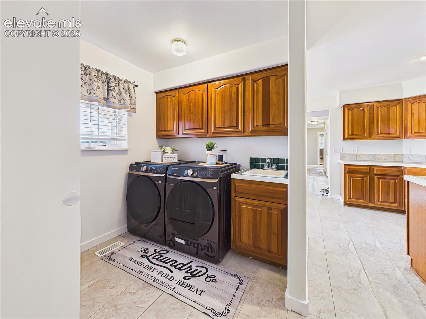 Convenient laundry room features upper cabinetry, utility sink, and dedicated workspace to help keep daily tasks organized and efficient.