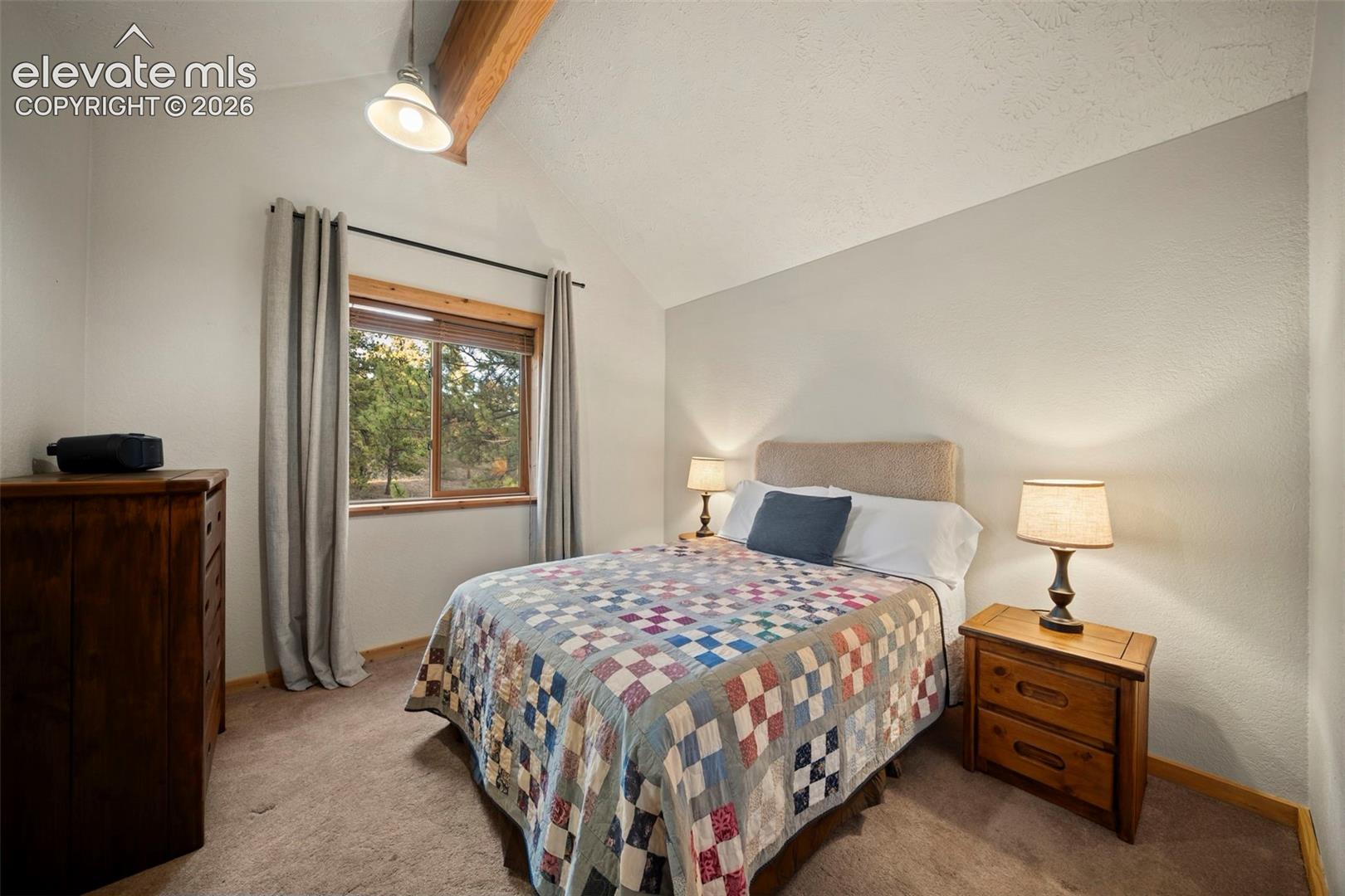 Vaulted ceiling featuring an exposed wood beam, natural wood-trimmed window, and neutral wall tones