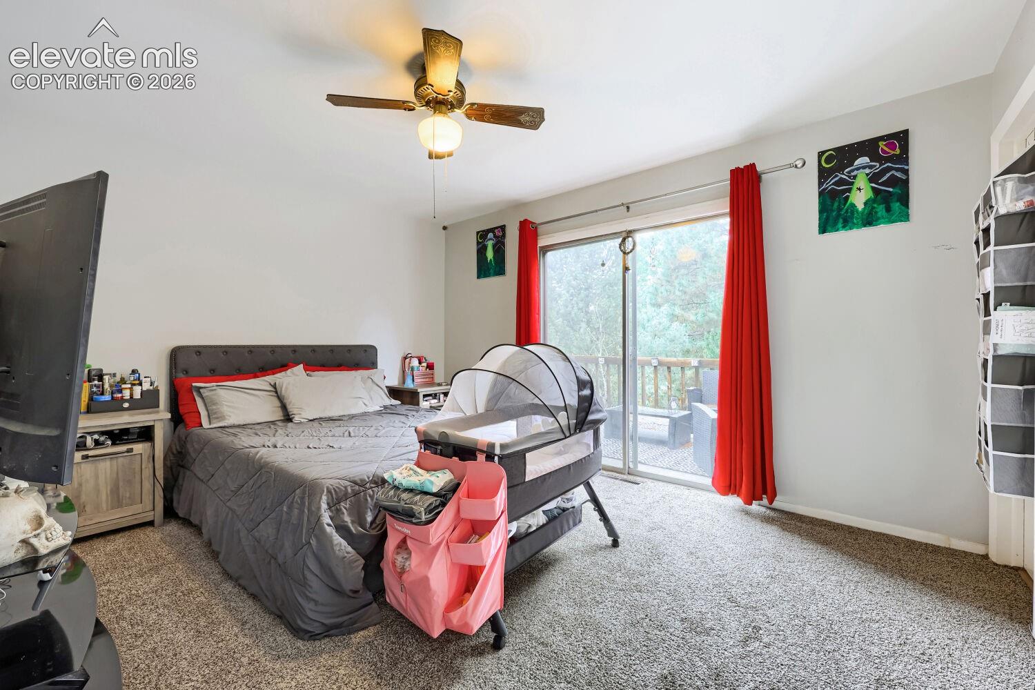 Room featuring neutral wall tones, carpeted flooring, a ceiling fan, and sliding glass doors leading to an outdoor deck