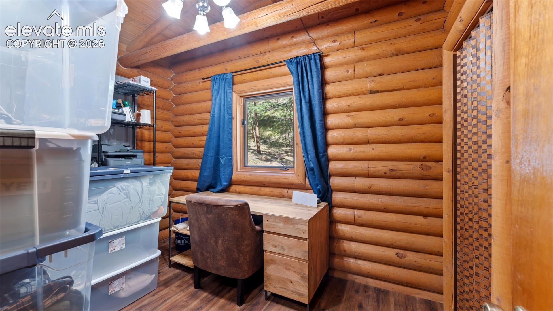Exposed log walls, vaulted ceiling with exposed beam, and multi-pane window