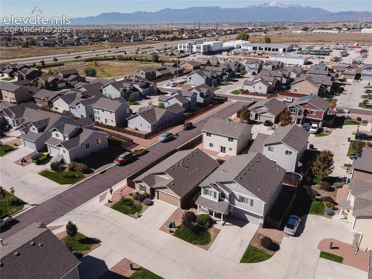 Mountain backdrop, residential street, concrete driveways, paved roads, and multiple single-family homes