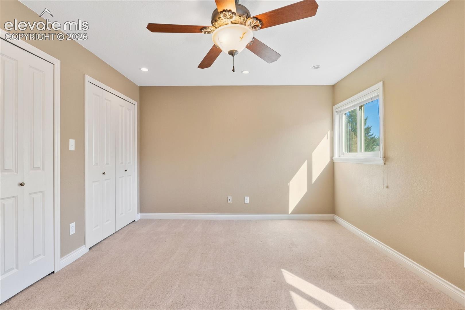 Neutral interior featuring wall-to-wall carpeting, dual-door built-in closet, recessed ceiling lighting, and a multi-blade ceiling fan with integrated light fixture