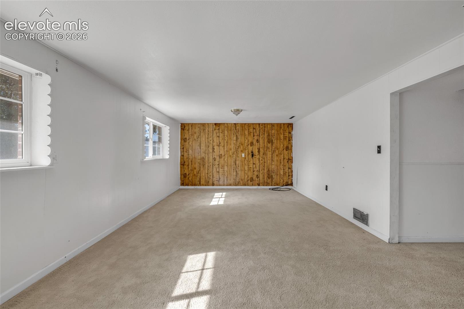 Wood-paneled accent wall with light beige carpeting and white painted walls