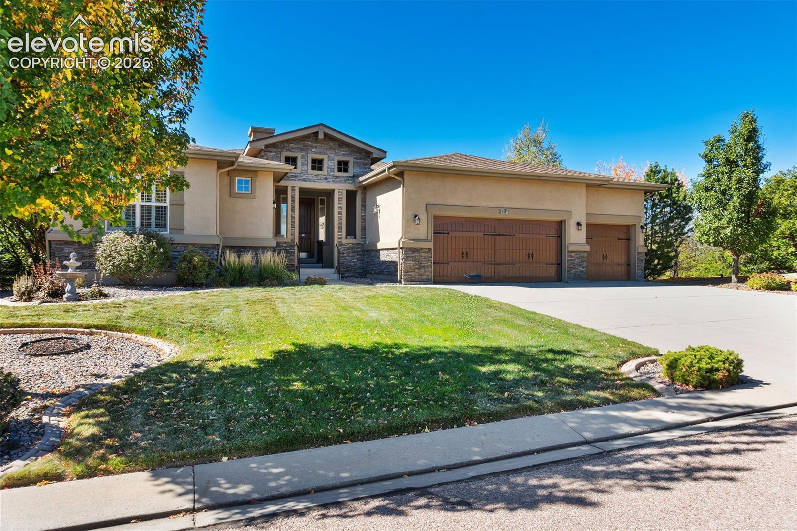 GORGEOUS STUCCO HOME WITH STONE  ACCENTS AND THREE CAR WOOD-STYLE GARAGE DOORS WITH LARGE DRIVEAWAY