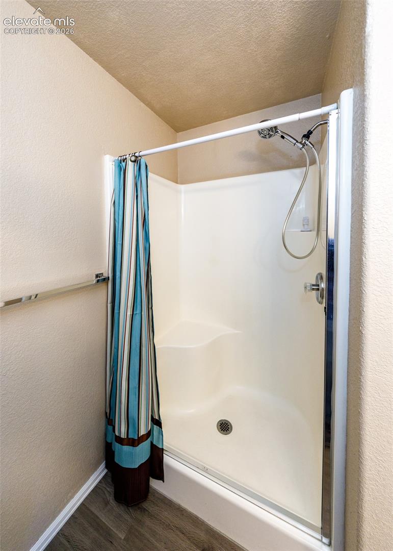 Shower stall featuring a molded surround with integrated seating, chrome hand-held showerhead, and a glass door with a polished chrome frame