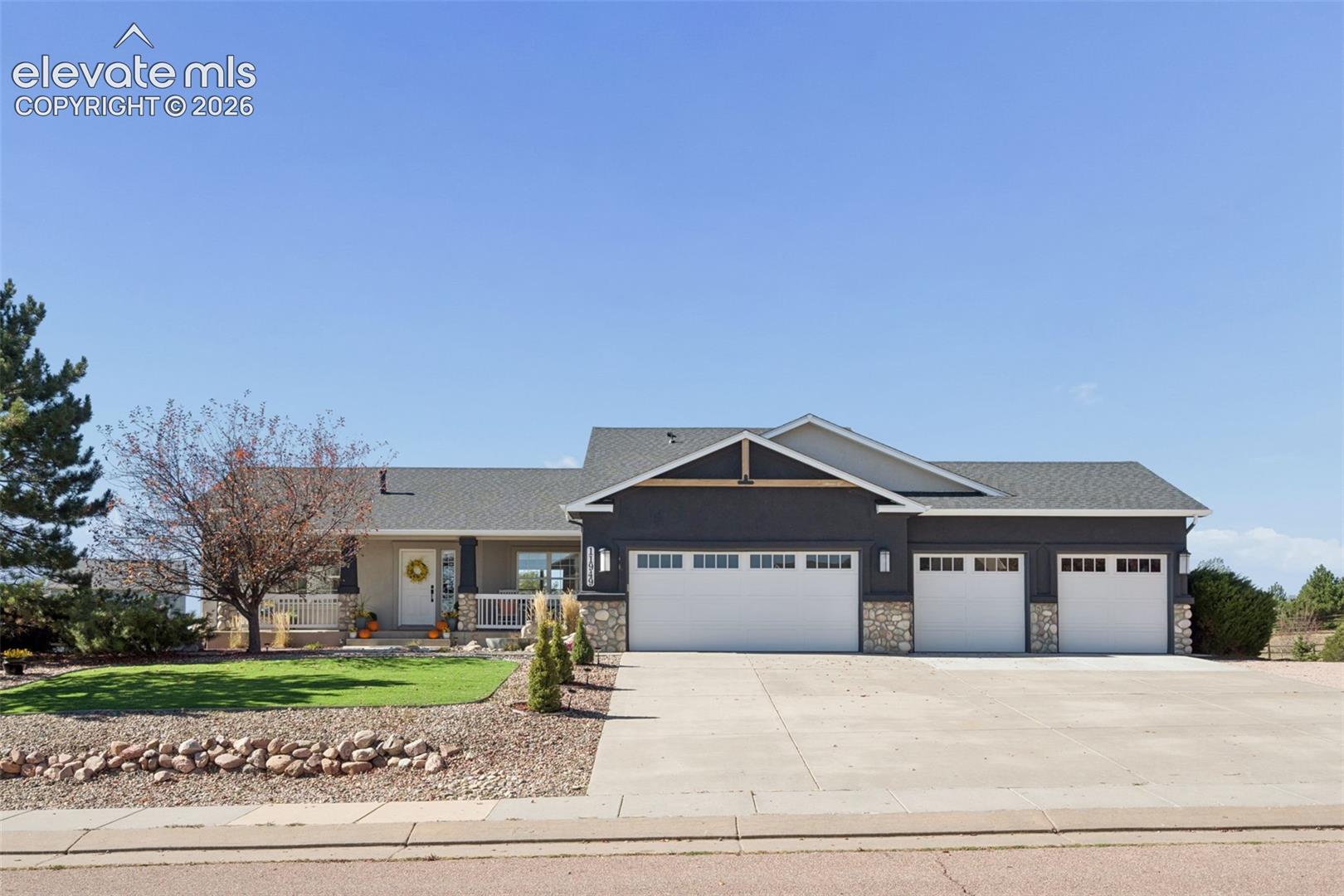Exterior featuring a substantial driveway, a three-car garage, and a covered porch